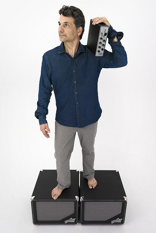 Aguilar Artist John Patitucci carrying amp while standing on cabinet